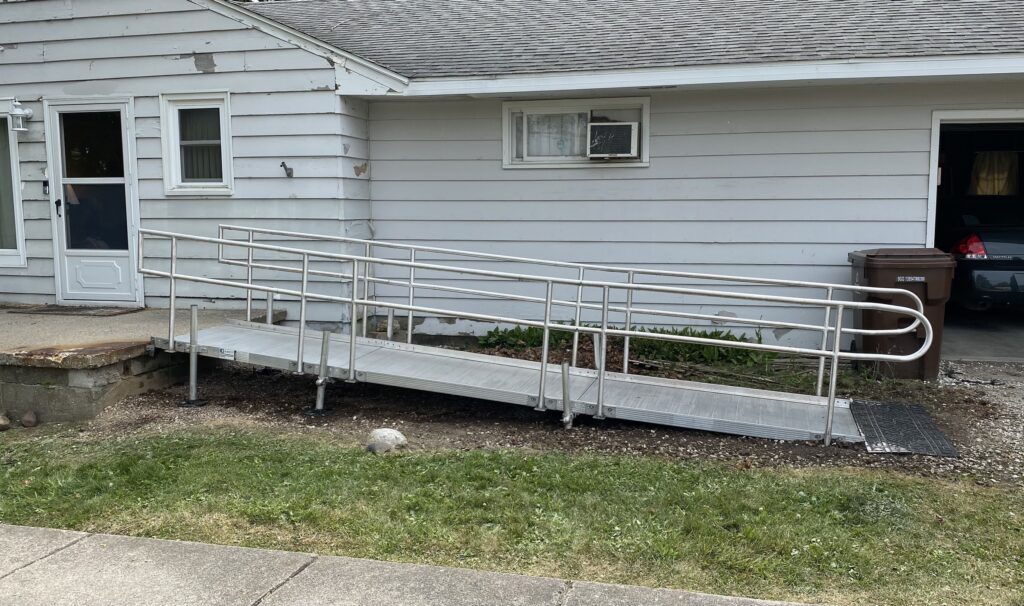 New aluminum wheelchair ramp installed at front entrance replacing old wooden ramp for improved safety and accessibility