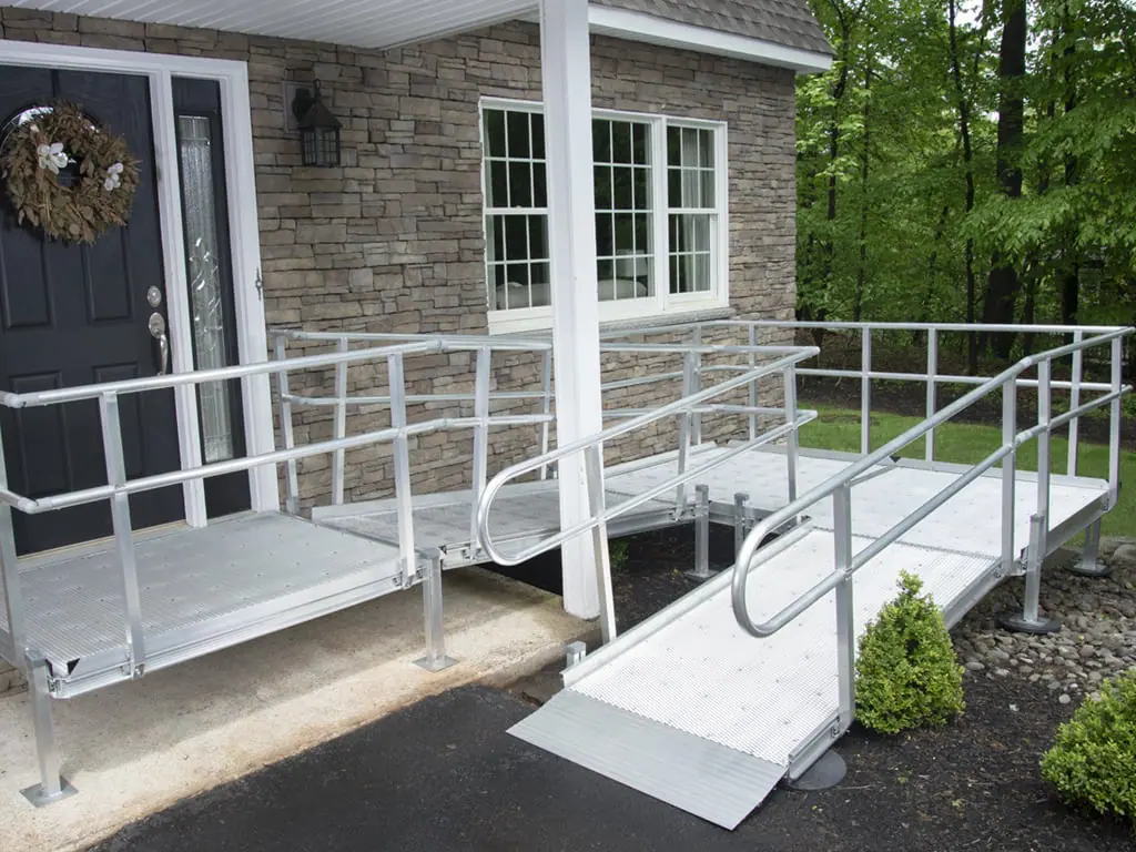 Aluminum wheelchair ramp leading from driveway to front door with multiple turns for safe and gradual entry