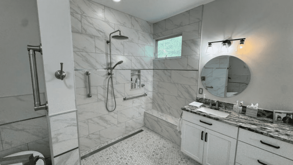 Accessible bathroom with walk-in shower, non-slip tile flooring, grab bars, and built-in shower bench for safe aging in place