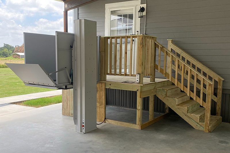 Vertical platform lift installed beside stairs for accessible home entry